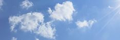 an airplane is flying high in the blue sky with white clouds and sunbeams