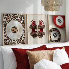 three framed pictures hang on the wall above a bed with red pillows and leopard print