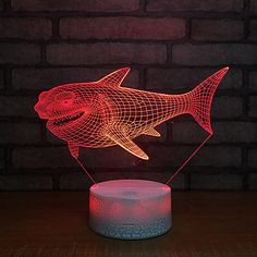 a red shark lamp sitting on top of a wooden table next to a brick wall