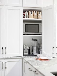 a kitchen with white cabinets and marble counter tops in the center is a coffee maker