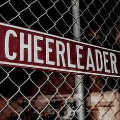 a red and white sign that reads cheerleader behind a chain link fence