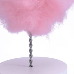 a pink fuzzy ball on top of a white table with a metal spiral in the middle