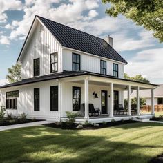 a large white house with black roof and windows on the front porch, surrounded by lush green grass