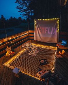 a lit up bed on top of a wooden deck next to a string light fence