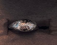 a silver ring sitting on top of a brown cloth covered floor next to a wall