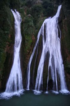 two large waterfalls in the middle of a body of water