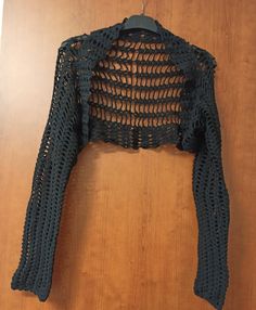 a crocheted jacket hanging on a wooden wall