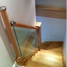 a wooden stair case with glass railing and handrail