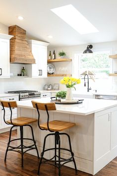 a kitchen with two stools in front of the island and an oven above it