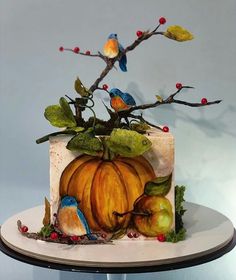 there is a cake decorated with birds and pumpkins on the top of a table