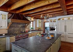 a large kitchen with white cabinets and granite counter tops, along with wooden ceiling beams