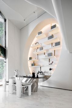 a modern kitchen with white walls and marble flooring, built into the side of a curved wall