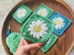 a person is holding up some crocheted granny's squares with flowers on them