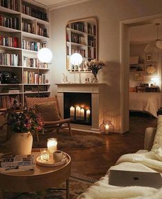 a living room filled with furniture and bookshelves next to a fire place covered in candles