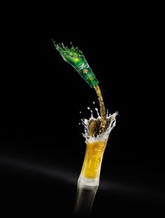 a beer being poured into a glass with water splashing from the top and bottom