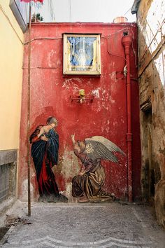 a painting on the side of a building with an angel sitting next to a woman