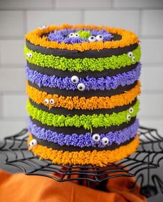 a multi - colored cake with googly eyes and spider webs on the side