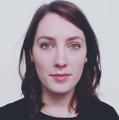 a woman with long hair and blue eyes looks at the camera while wearing a black shirt