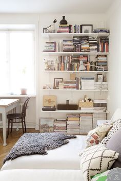 a bedroom with a bed, desk and bookshelf filled with books in it