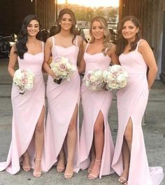 bridesmaids in pink dresses posing for the camera with their bridal bouquets