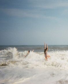 two people playing in the water on their surfboards at the beach while another person watches