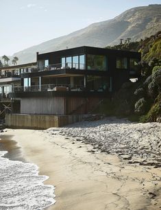 a house on the beach with mountains in the background