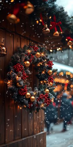 a christmas wreath hanging on the side of a wooden building with lights and decorations around it