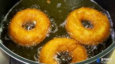 three doughnuts frying in oil in a pan