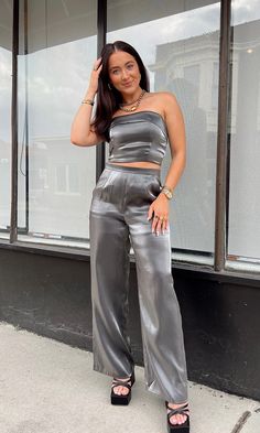 FINAL SALE It's giving GLAM. This gunmetal metallic strapless top with a fold over neckline would be PERFECT for a night out in the city! Pair it with our "Giving Glam Pant" to complete the set. Model is 5'2" with a 34A bust, 25" waist, 34" hips, and wearing a size small. Model usually 2/4. This item runs true to size! Satin Clothing, Glam Tops, Satin Pants, Satin Blouses, Silver Tops, Feminine Beauty, Black Media, Fold Over, Satin Dresses