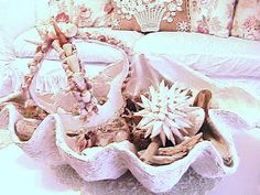 a basket filled with flowers sitting on top of a bed next to pillows and pillow cases