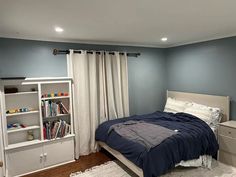 a bedroom with a bed, bookcases and a dresser in it's corner