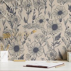 a desk with a notebook, pen and flower wallpaper