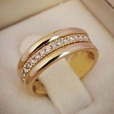 two gold wedding rings in a box with diamonds on the inside and outside of them