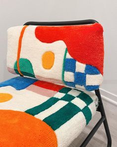 a multicolored towel sitting on top of a folding chair in front of a white wall