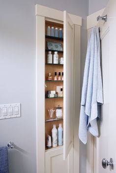 an open door in a bathroom next to a towel rack with bottles and soaps on it