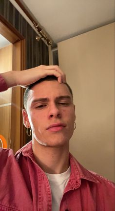 a young man is shaving his hair in the mirror while wearing a red shirt