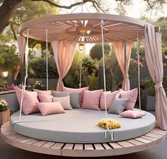 a circular swing bed with pink pillows and curtains on the top is surrounded by flowers