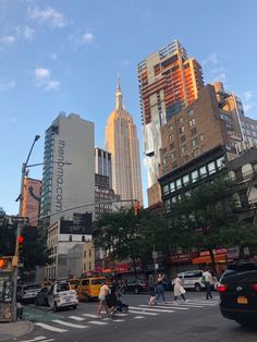 people crossing the street at an intersection in new york city, with skyscrapers in the background