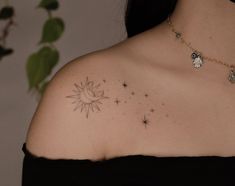 the back of a woman's shoulder with stars and a sun tattoo on it