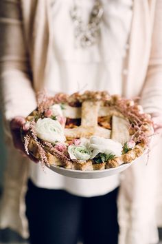 a woman is holding a bowl with flowers on it and a cross in the middle