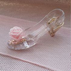 a glass shoe with a pink rose on the bottom and gold accents around the heel