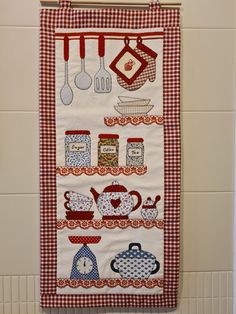 a kitchen towel hanging on the wall with utensils and teapots in it