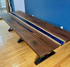 a wooden bench sitting on top of a hard wood floor next to a blue wall