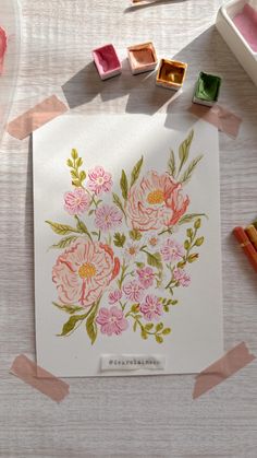 some pink flowers are on a white paper and some colored crayons with tape