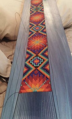 a wooden table with beaded designs on it's edge and pillows in the background