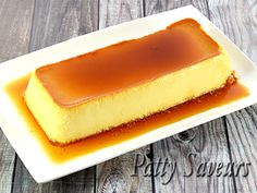 a piece of cheesecake covered in caramel sauce on a white plate with a wooden background