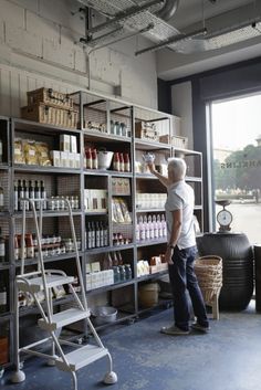 a man standing in front of a shelf filled with lots of bottles and containers next to a window