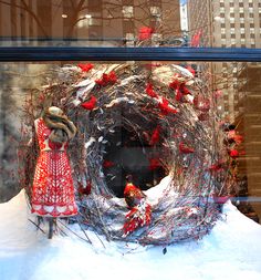 a wreath with red and white decorations is in the front window of a storefront