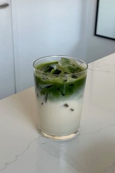 a glass filled with liquid sitting on top of a counter next to a white wall