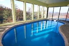 an indoor swimming pool with large windows on the side and blue water in the middle